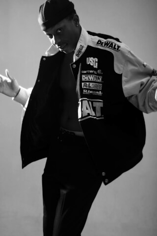 A person is confidently wearing a black and white jacket, photographed in a studio setting.