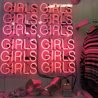 A vibrant neon sign spelling 'girls' in a playful retail setting, perfect for fashion and youth culture promotions.