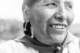 A smiling woman shows off a gold tooth in this close-up black and white portrait.