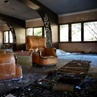 Two vintage armchairs sit amidst the decay of an abandoned building, a testament to forgotten elegance.