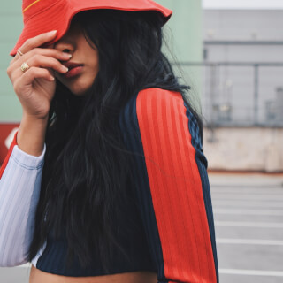 A stylish woman wearing a red Nike bucket hat poses in an urban setting.