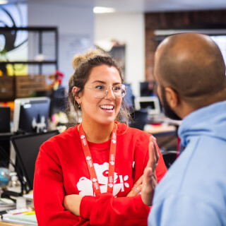 Two colleagues are having a cheerful conversation in a modern office setting.