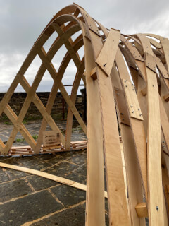 A wooden structure made of plywood stands outdoors showcasing modern architectural design and construction.