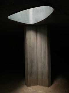 A low-angle view of a concrete column under a skylight, creating an abstract and moody architectural scene.