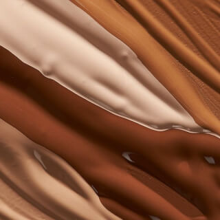 Close-up of foundation swatches in various skin tones, showcasing texture and color range for beauty and cosmetic advertising.