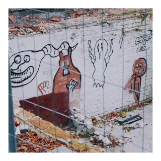 Graffiti art on a brick wall features cartoonish monster and ghost figures in an urban outdoor setting.