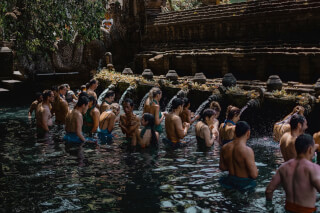 People participate in a cleansing ritual at Tirta Empul Temple, Bali, immersing themselves in holy spring water.