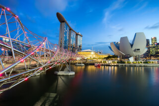 Singapore's iconic Marina Bay Sands and Helix Bridge illuminated at night, reflecting on the water.