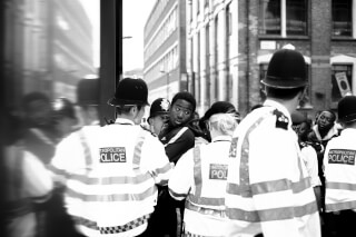 A group of Metropolitan Police officers are seen on a city street in a black and white shot.