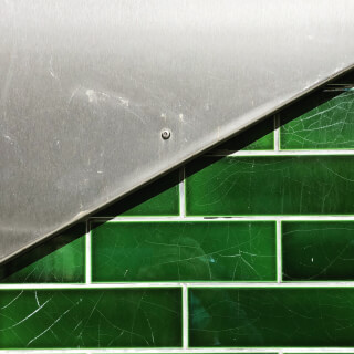 A close-up shot of green tiles and a metal panel creating a geometric composition, perfect for design and renovation themes.