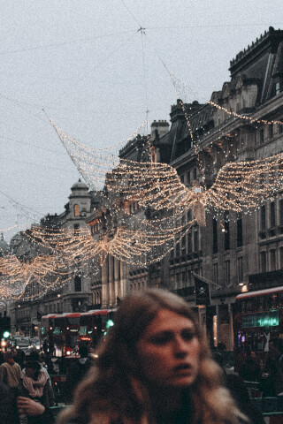 A street scene in London, UK, decorated for Christmas with illuminated angel lights hanging across the buildings.