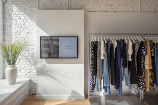 A retail space features a screen and clothing rack, offering a modern shopping experience in a bright, inviting setting.
