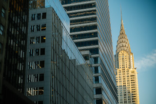 A view of the Chrysler Building framed by modern skyscrapers in a vibrant urban setting.