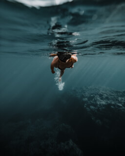 A woman snorkeling underwater, surrounded by the ocean's depths in this natural scene.