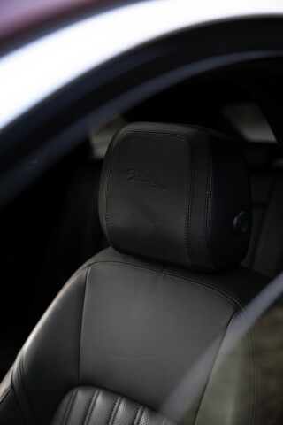 Close-up of a Jaguar car seat headrest featuring the brand's logo, showcasing the luxurious leather interior.