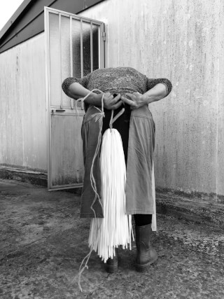 A person in an apron stands with their back to the camera, holding a mop behind them.