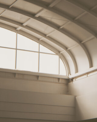 Interior view showcasing modern architecture with a vaulted ceiling and window, bathed in soft light.