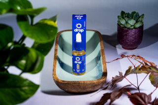 Close-up product shot of Drop CBD oil with chamomile, promoting relaxation and wellness in a modern, minimalist style.