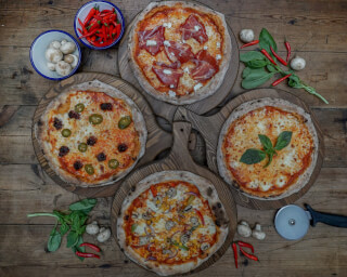 Overhead shot of various pizzas with toppings on a wooden table, showcasing a delicious selection of Italian cuisine.