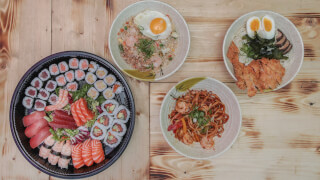 A selection of Japanese dishes including sushi, ramen, noodles, and fried rice arranged on a wooden table.