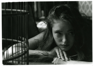 A captivating black and white portrait of a woman holding a feather, evoking a vintage and artistic mood.