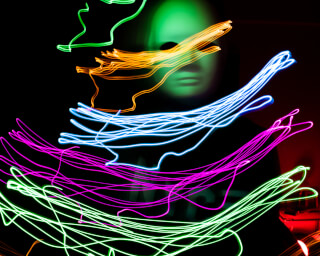Abstract light painting of a masked person in a dark room, creating a mysterious and artistic vibe.