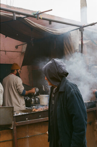 A vendor cooks at a street food stall in a traditional urban setting, showcasing the local food culture.