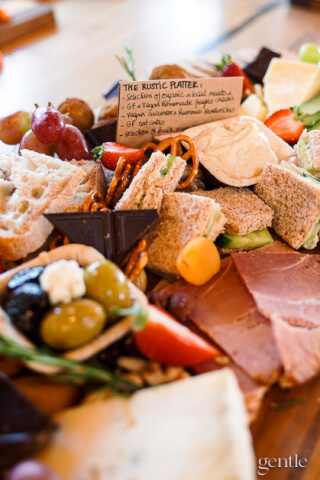 A close-up shot of a rustic charcuterie board filled with various cheeses, meats, olives, and bread.