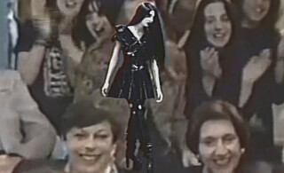 A goth woman in a black dress and boots stands out from a crowd of onlookers in this vintage image.