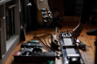 A musician prepares to play instruments including guitar and lap steel guitar in a cozy studio space.