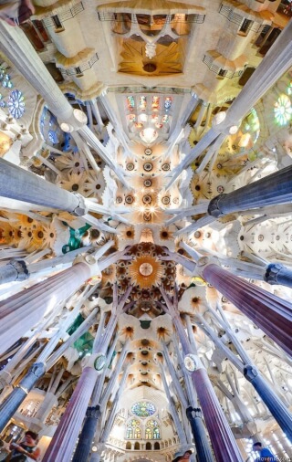 View of the ceiling inside the Sagrada Familia in Barcelona, Spain, showing ornate columns and intricate designs.
