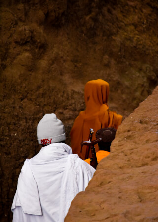 Three religious figures stand near a rock formation, creating a tranquil scene of cultural significance and heritage.