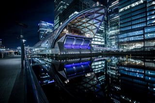 Night view of modern architecture reflecting in the water in an urban city landscape.