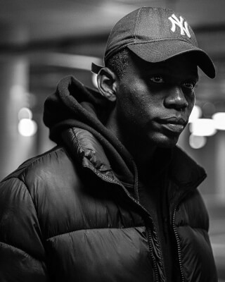 Portrait of a man wearing a new york yankees cap in a black and white urban scene.