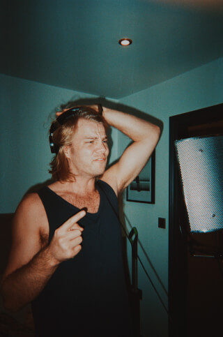 A singer wearing headphones in a recording studio with a microphone, bathed in warm, artificial lighting.