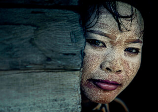 A striking close-up of a woman's face adorned with intricate tribal face paint, portraying a cultural beauty.