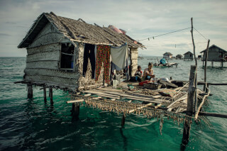 A traditional stilt house village in the sea shows people living a subsistence fishing lifestyle.