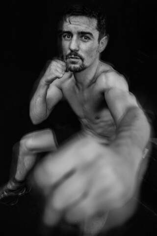A muscular boxer in black and white delivers a powerful punch, showcasing strength and determination for fitness and sports marketing.