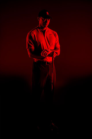 A dramatic studio shot of a male golfer in red light with a determined expression.