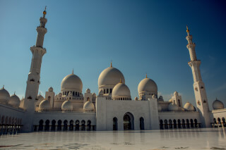 The Sheikh Zayed Grand Mosque in Abu Dhabi showcases stunning Islamic architecture under a clear blue sky.
