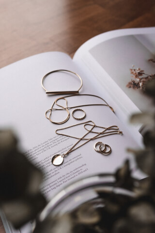 Elegant gold jewelry arranged on an open book page, showcasing minimalist design and sophistication.