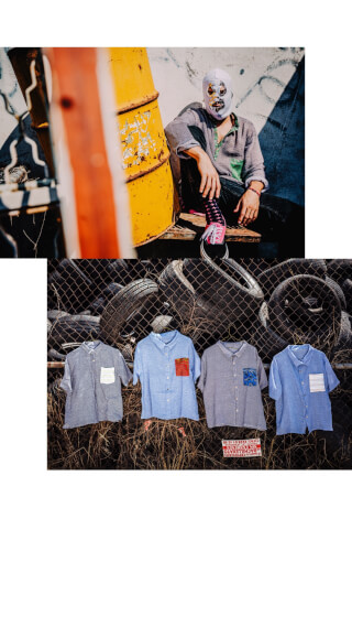 A man in a luchador mask sits next to shirts on a fence made of tires for a unique streetwear fashion shoot.