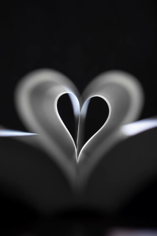 A delicate paper heart against a dark background expresses love and tenderness in this studio close-up.