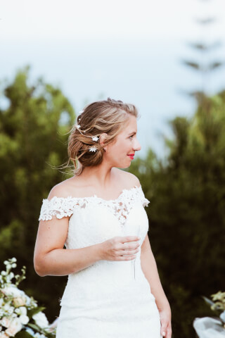 A bride in a white dress looks off to the side while holding a champagne flute at her wedding.
