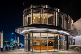 A modern cafe building at night with an inviting outdoor seating area, promoting an urban lifestyle.