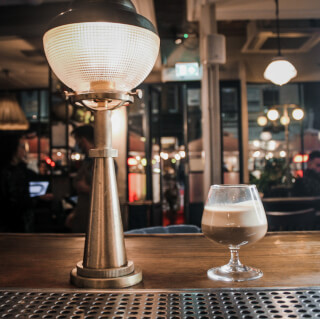 A cozy bar scene with a layered cocktail and a vintage lamp creating a warm, inviting atmosphere.