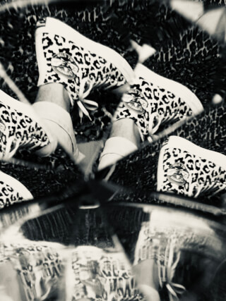 A creative black and white shot showcases leopard print Converse sneakers in a fun, mirrored perspective.