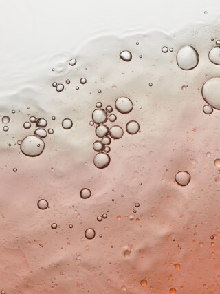 Abstract close-up of clear bubbles in a soft peach-toned liquid. Ideal for skincare, beauty or wellness concepts.
