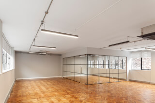An empty modern office space with wood floors and glass partitions, ready for business.