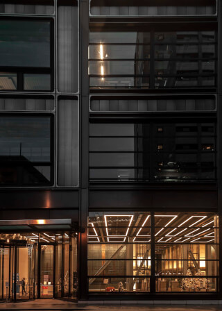 Modern building facade with illuminated entrance and revolving doors at night.